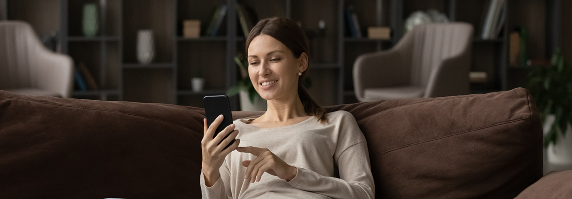 a woman uses her mobile phone while relaxing on a couch