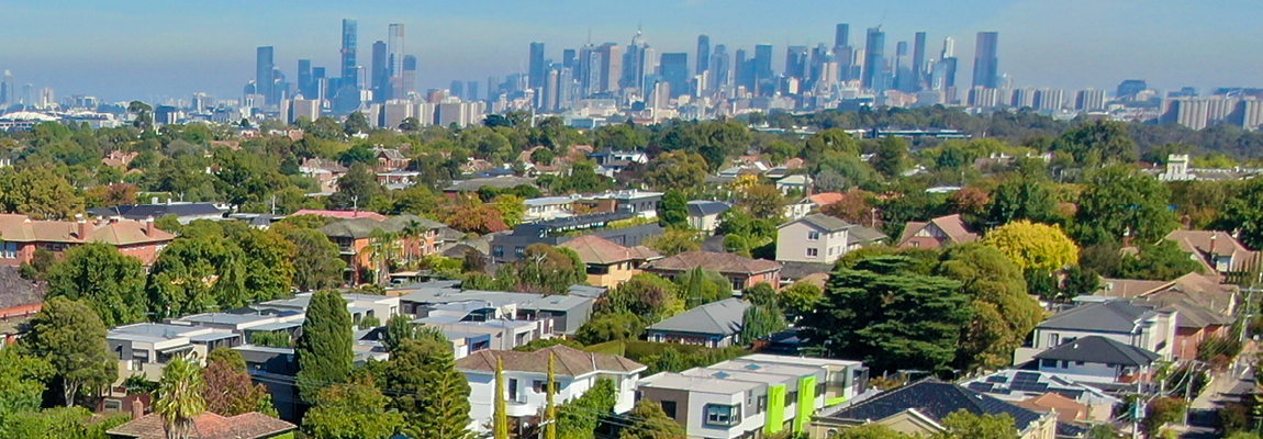 aerial view of suburban trees and houses with Melbourne city skyline in the background