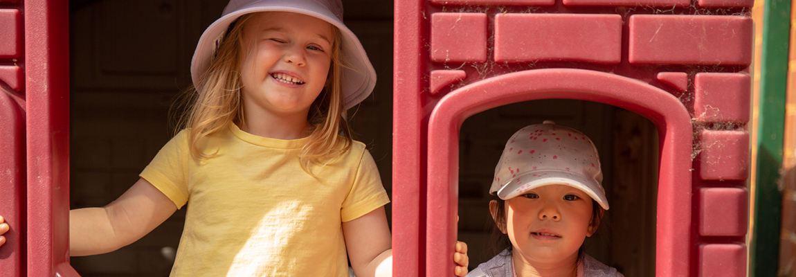 a preschool age girl winks next to a similarly aged boy in a plastic cubby