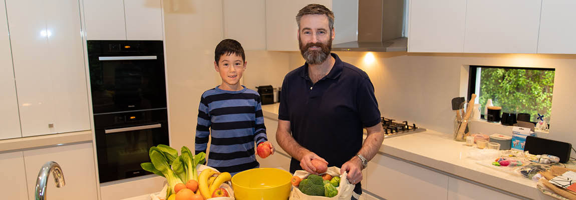 a 10 year old boy and middle-aged man unpack fruit and vegetables in a kitchen