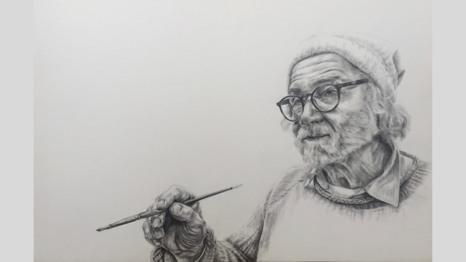 Older man wearing glasses, a beanie and a jumper, holding a paintbrush.