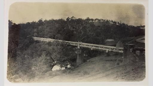 Old and worn photo of pipes bridged across a river