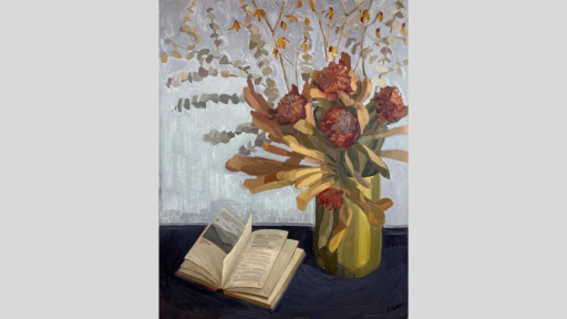 A bouquet of waratahs in a vase next to an open book