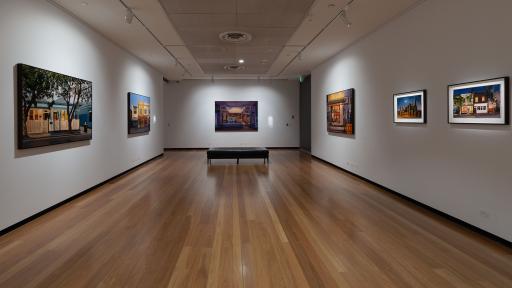 View of paintings of buildings hanging on walls in an art gallery