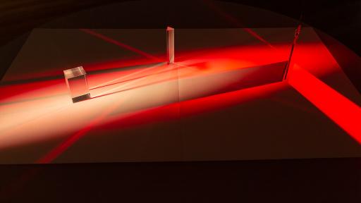 Art installation featuring two clear objects and projected red and black colours.