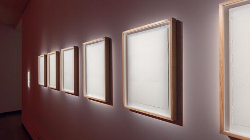 Art installation featuring six white squares hanging on a wall, with squares appearing smaller when further from camera.