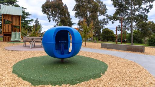 Playground showing blueberry spinner in foreground and other play equipment in background including timber unit and swings