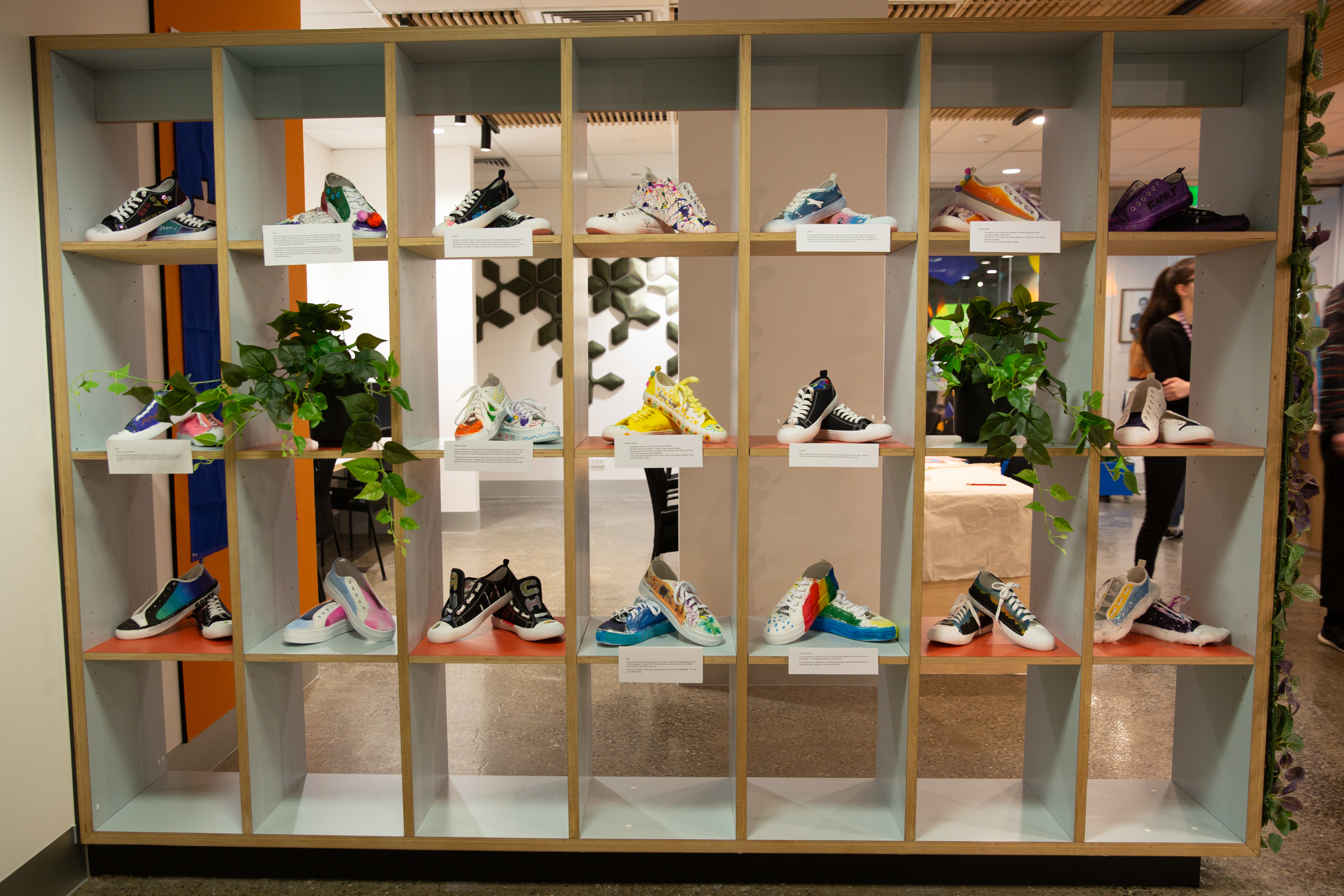 An art installation of colourful sneakers displayed on wooden shelves