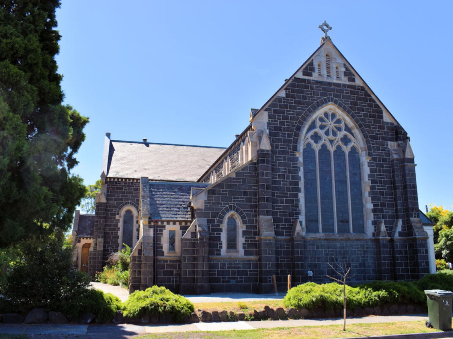 A bluestone church with a large arched window.