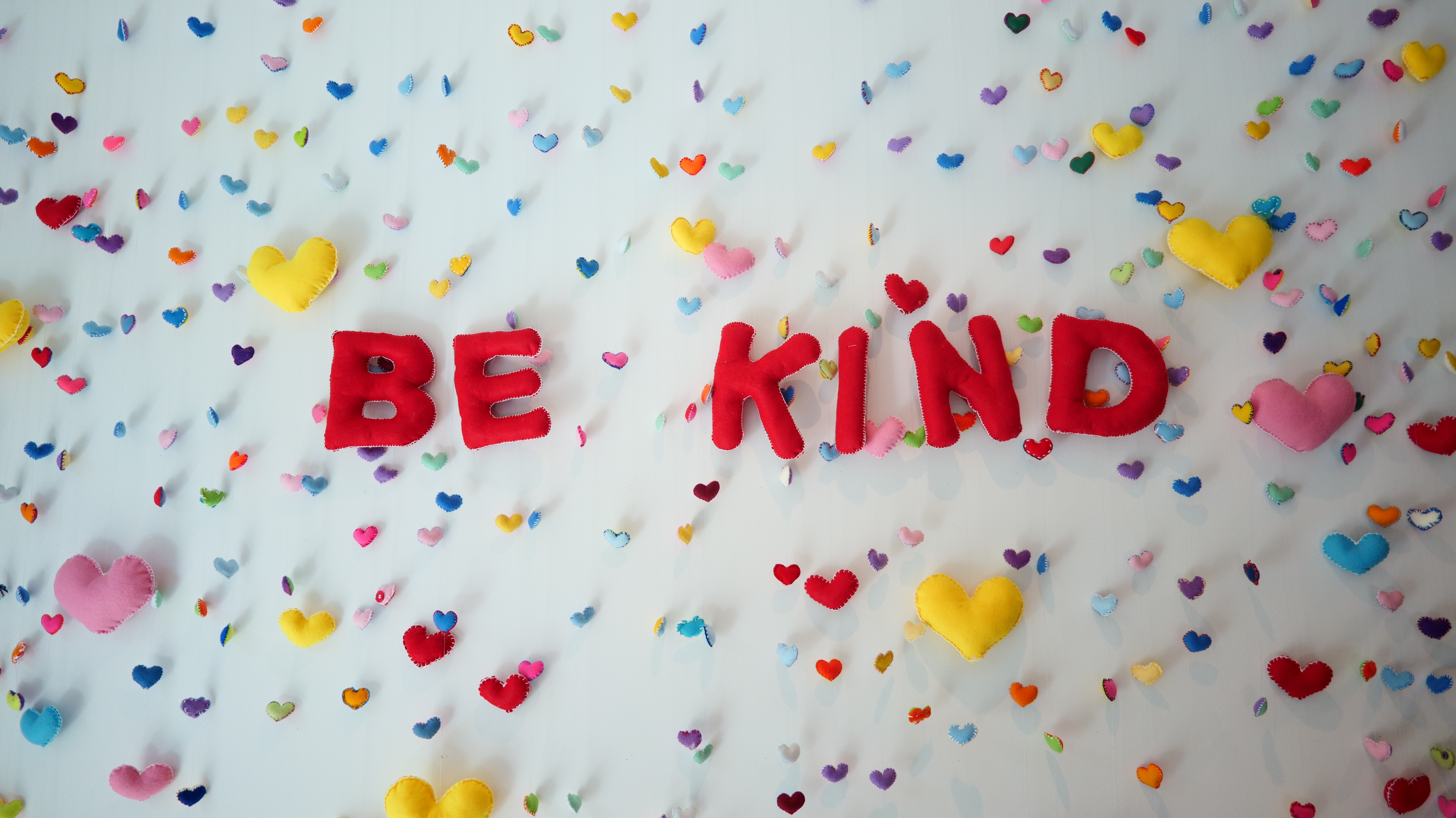 Red felt letting of 'Be Kind' written and surrounded by many small multi-coloured felt hearts