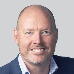 a smiling man in a suit with a shaved head