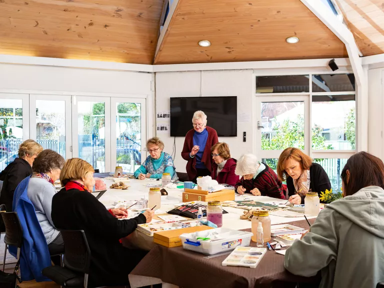 A group of people sit around a table during an art class at Surrey Hills Neighbourhood House