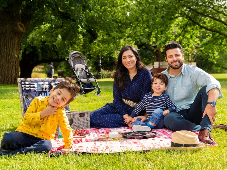 A family of 4 having a picnic in the park.