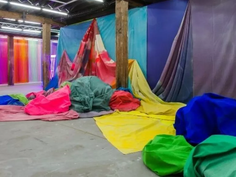 large sheets of canvas painted with bright colours and draped across the walls and piled on the ground