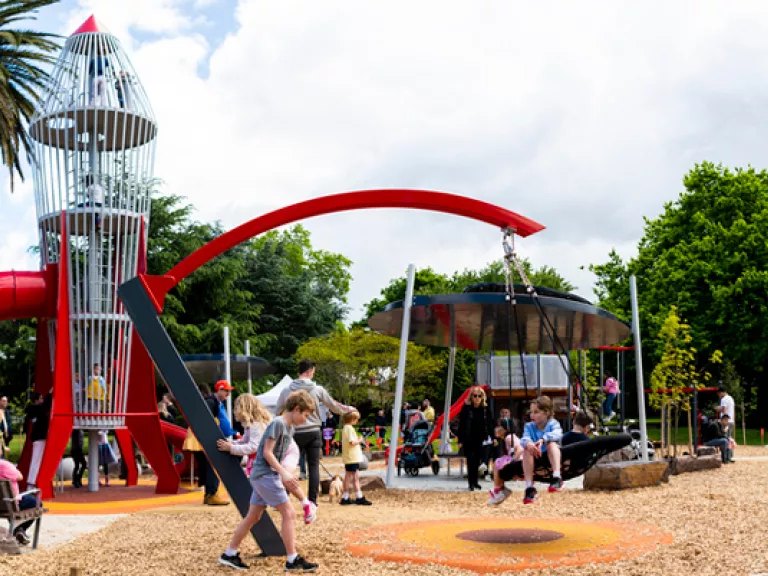 A children's playground with a big, climbable rocketship as the feature