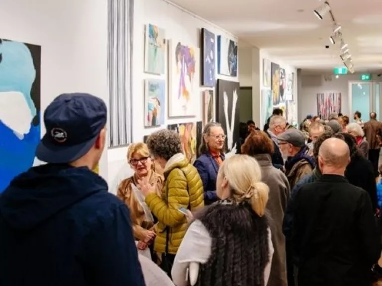 Group of people milling around artworks in a gallery