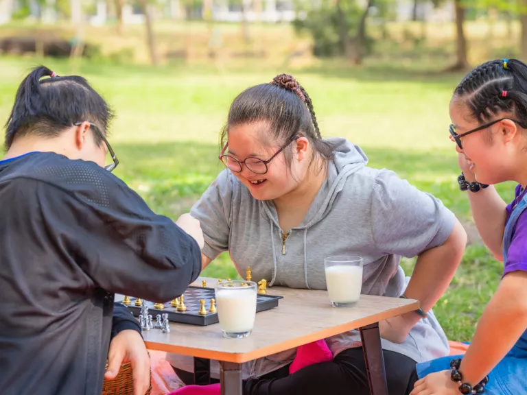 3 people playing chess and having a picnic