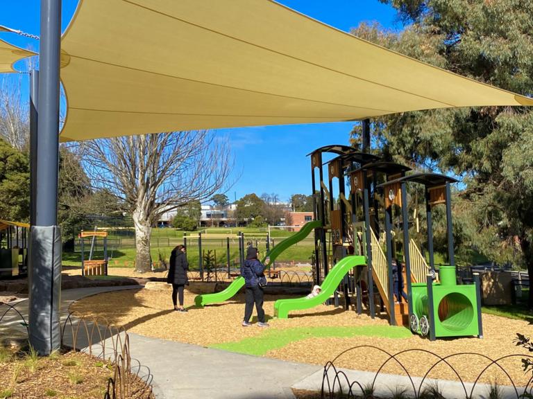 A small playground covered by a large shade sail