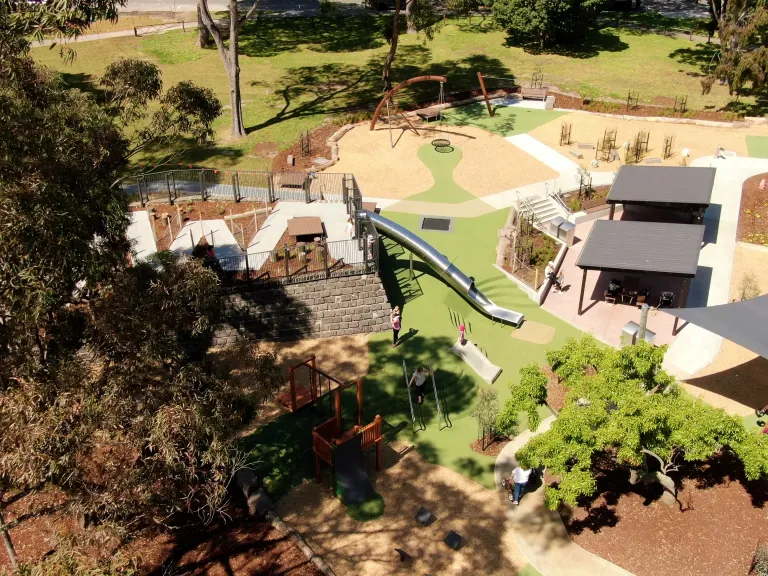 birds eye view of a playground with trees and picnic shelters