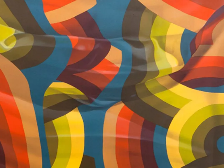 A painting featuring close folds of a piece of patterned fabric. The pattern features bold curves, varying in shades of red, green, and yellow on a blue background.  