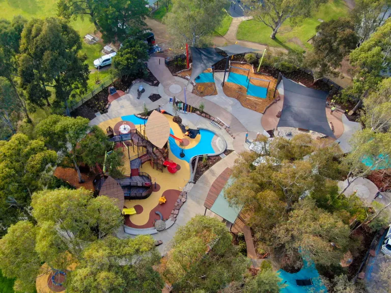 A birdeye view of a large playground surrounded by trees 