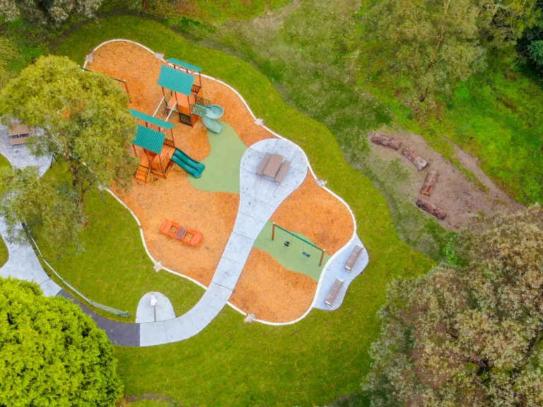 Aerial view of a playground surrounded by green grass and trees