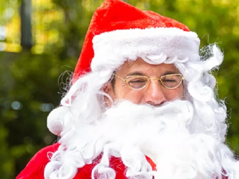 man with a big white beard, and a red hat edged with white