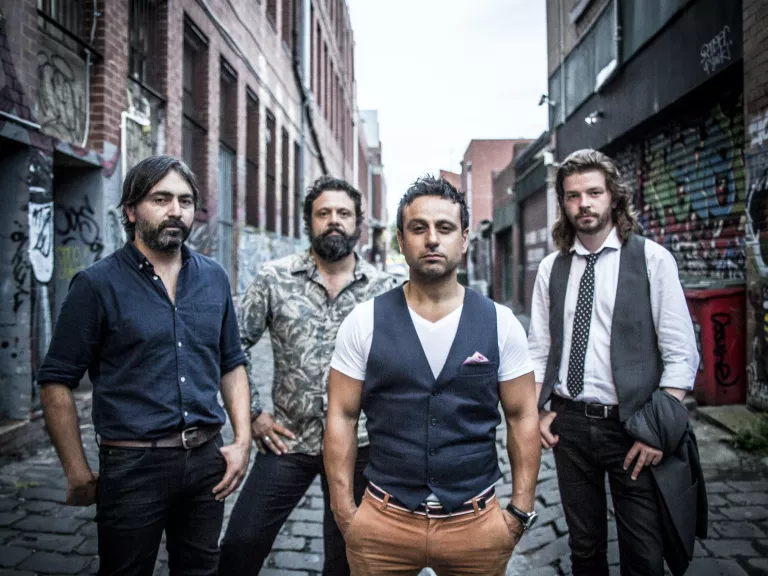 4 men standing in a cobblestone alleyway