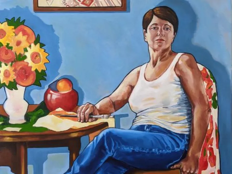 A woman with short brown hair sits on a wooden chair with her legs crossed, staring outward. She wears a white singlet, blue jeans, and black lace-up shoes. Her right hand rests on an open book on a round wooden table, alongside a vase of orange and yellow flowers and a red fruit bowl. Sky blue wallpaper with a framed painting of a similar composition hangs behind her. The pale red carpet has purple diamond patterns and two books lie on the floor: Seeing Ourselves: Women’s Self Portraits by Frances Borzello