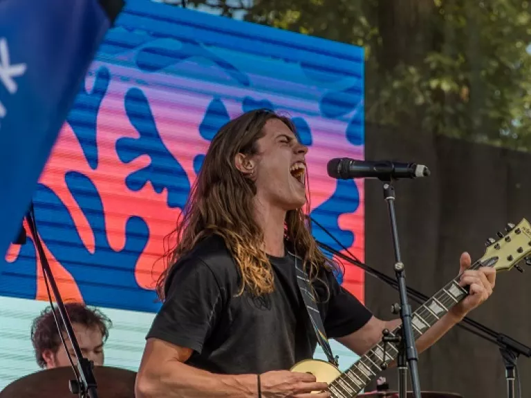 Young person with a guitar performing at summer in the park