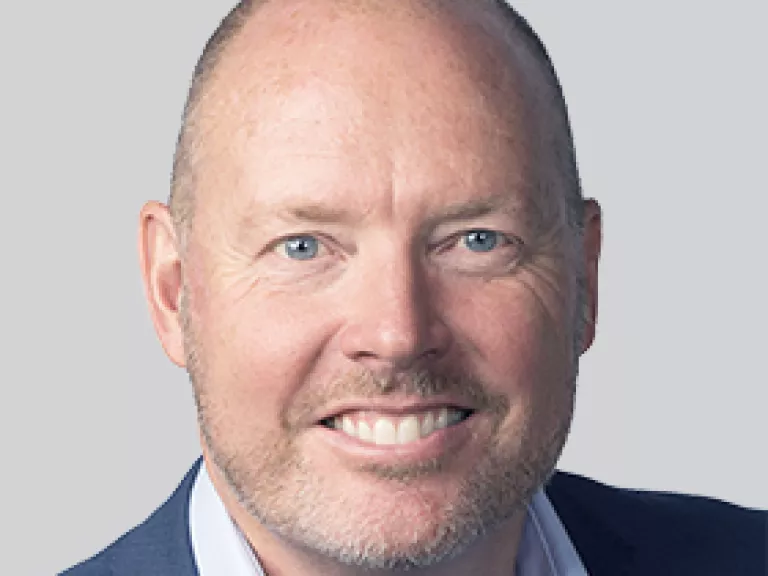 a smiling man in a suit with a shaved head