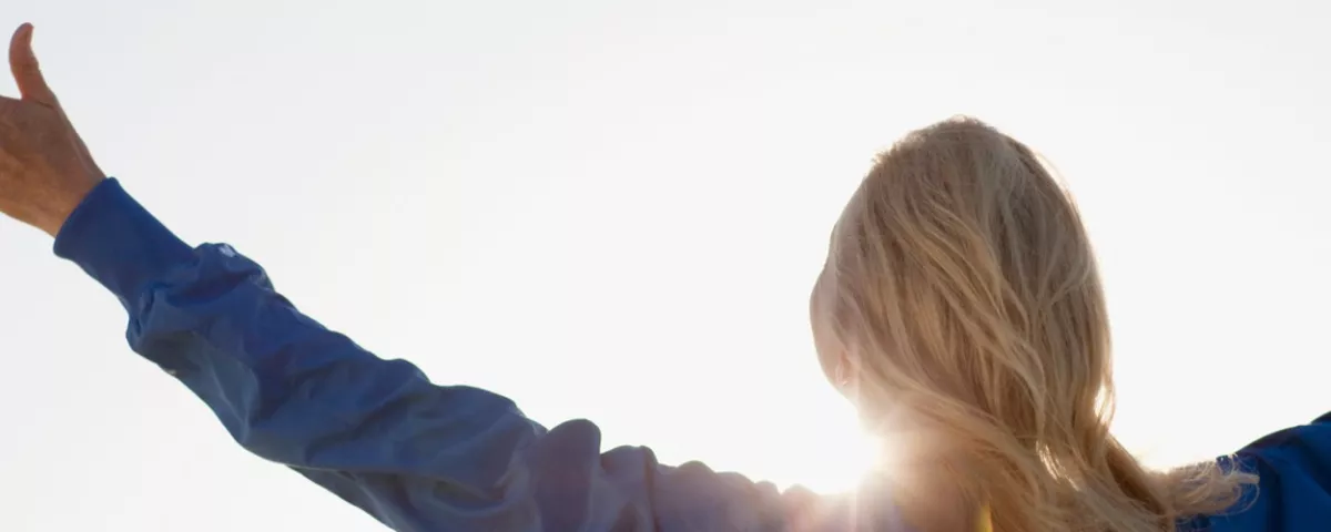 Woman with hands outstretched facing the sunshine