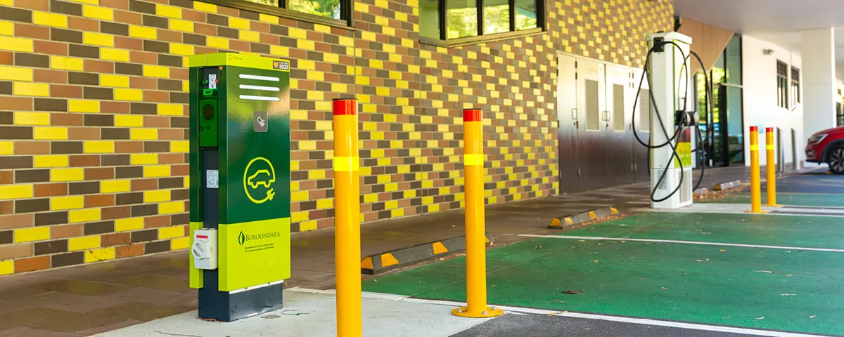 Green metal-clad charger box in parking bay with second white charger in background.