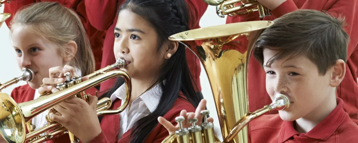 3 primary school children playing large brass instruments