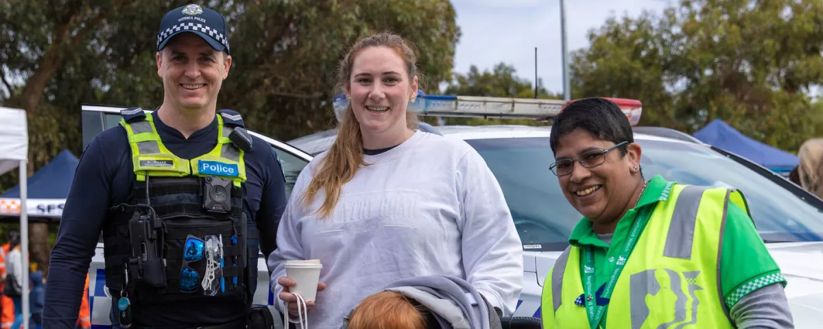 4 adults and a child smiling at the camera. One is wearing a police uniform, and one is wearing a high vis safety vest