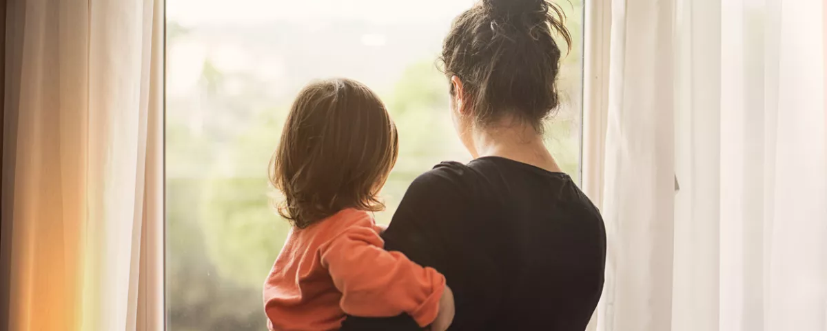 Mother holding child looking out of window