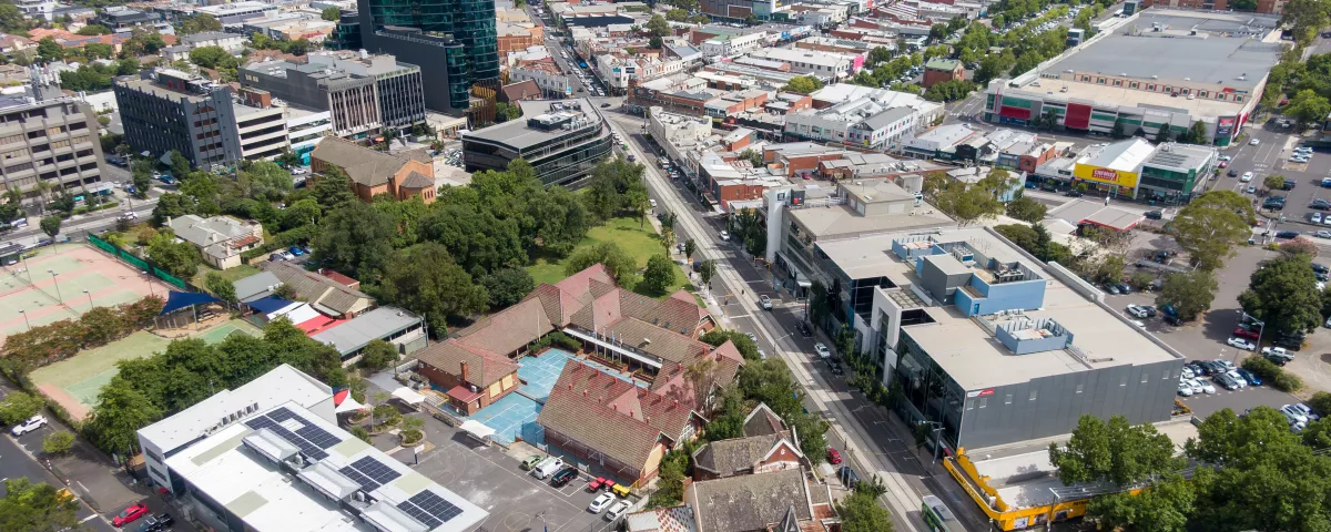 An aerial view of the Camberwell Civic Precinct, showing the surrounding landscape. The area is filled with buildings, trees, and pathways, making it a vibrant and welcoming public space. 