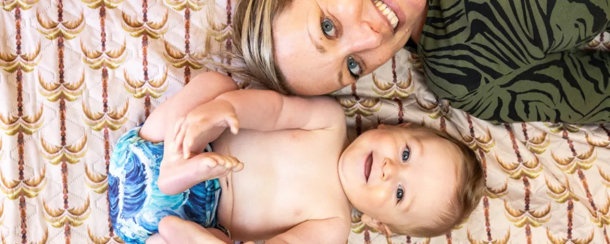 Baby wearing reusable nappy lies beside mother