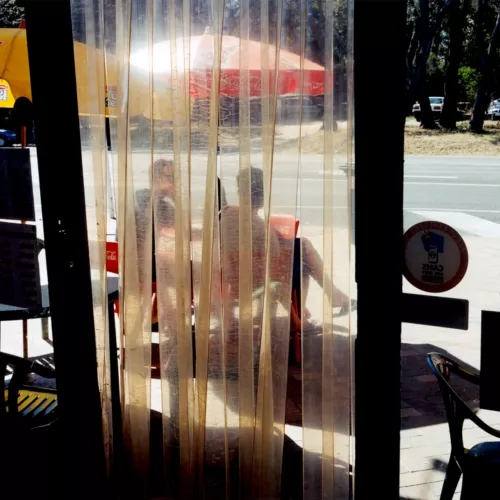 An old photo of two people sitting outside a cafe