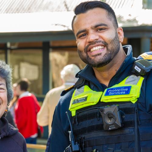 Older woman stand outdoors with a Victoria Police officer, both are smiling