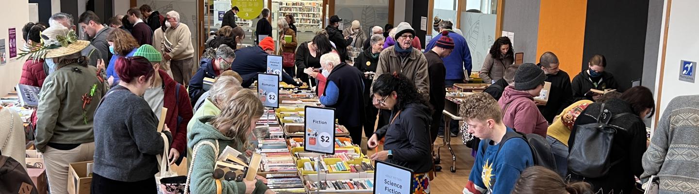 People rummage through boxes of used books on trestle tables