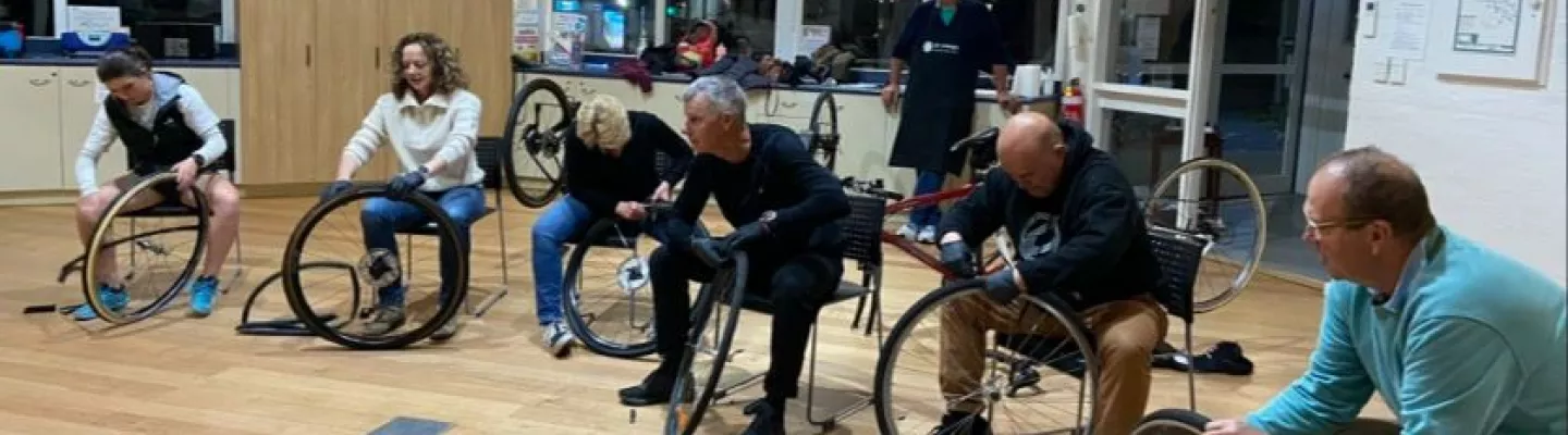 group of people sitting indoors with bike wheels in front of them