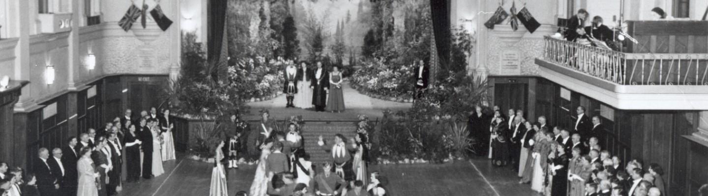 Historic photo of a grand ball at Hawthorn Town Hall, featuring elegantly dressed attendees and a live band performing on stage.