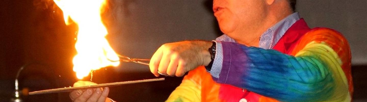 Person in rainbow shirt with fire sticks in hand