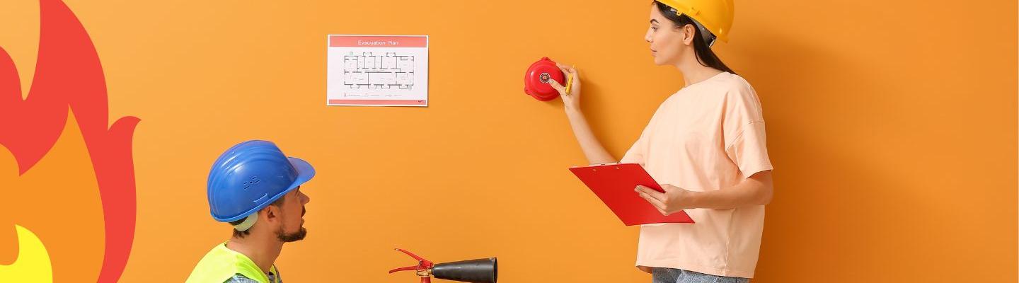 two peoploe wearing hard hats in front of an orange wall