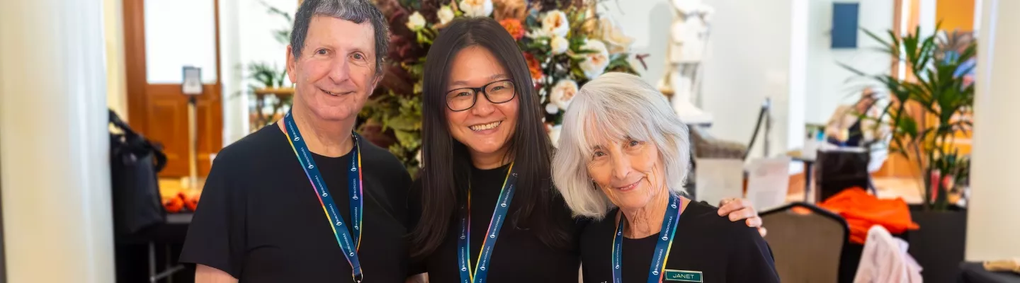 A middle-aged man, a younger woman and an older woman with arms around each other