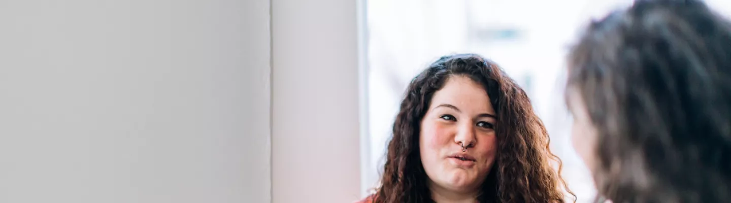 A woman with a cup of tea talks to another woman