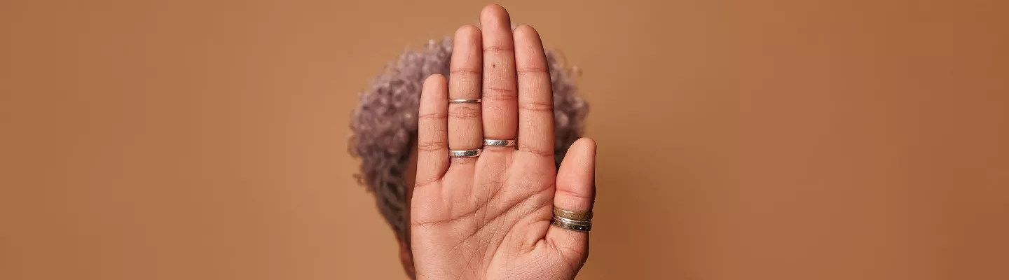  A woman with her arm and hand outstretched in front of her face gesturing to stop