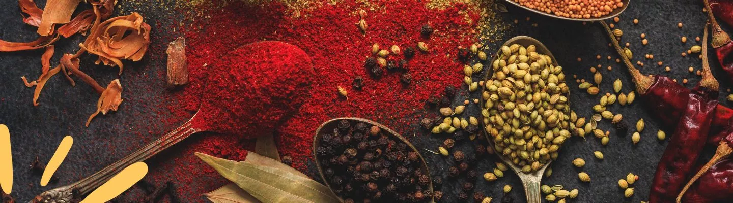 Colourful whole spices and powders on wooden spoons.