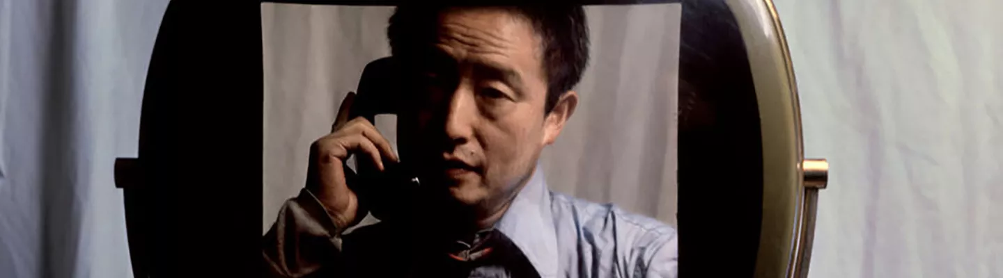 Photograph of a man holding a black telephone inside an old television screen